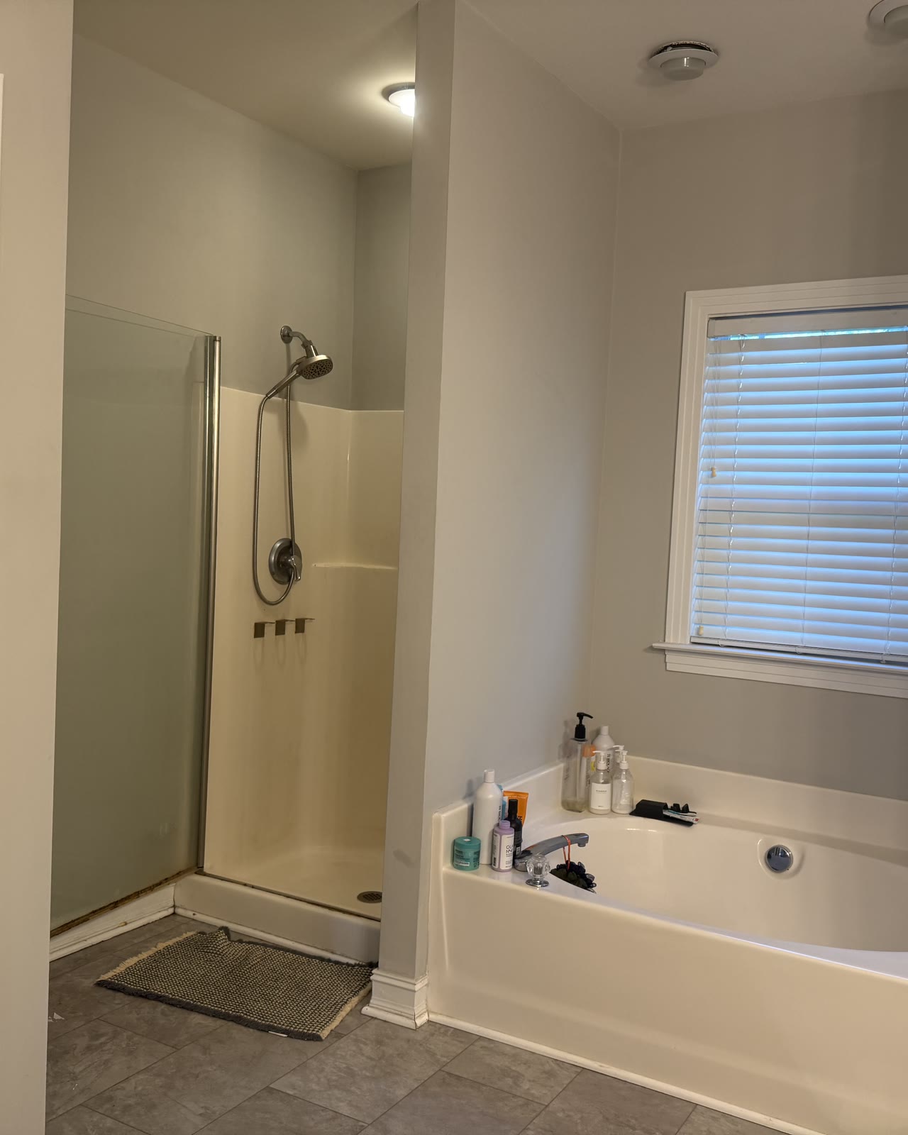Before: a builder-grade fiberglass shower insert with a framed door, next to a garden tub