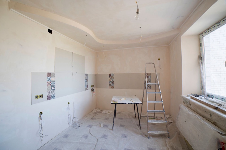 The kitchen stripped back to bare walls and floor, with a stepladder in the room