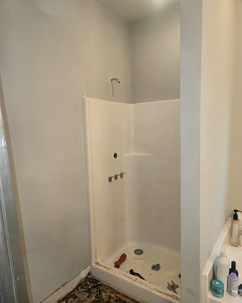 The original builder-grade fiberglass shower insert before demolition